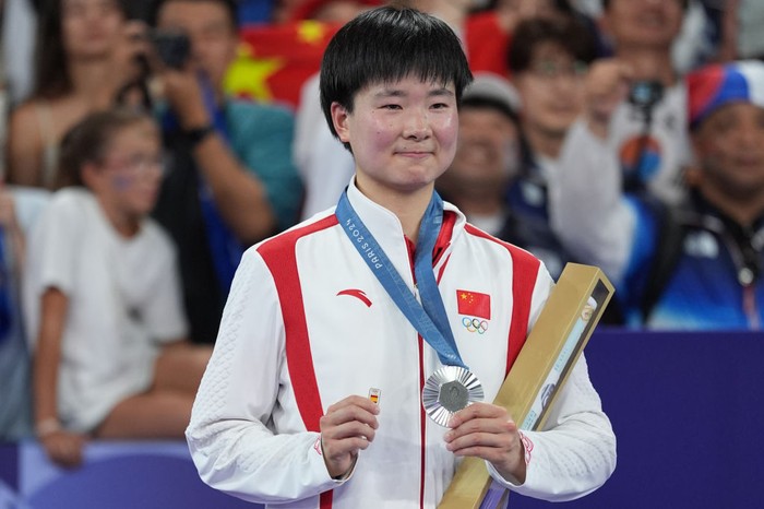 He Bing Jiao PARIS, FRANCE - AUGUST 05: Chinas silver medalist He Bingjiao celebrates on the podium during the medal ceremony after the Badminton - Womens Singles Gold Medal Match on day ten of the Paris 2024 Olympic Games at Porte de La Chapelle Arena on August 5, 2024 in Paris, France. (Photo by Nin Minzhe/CHINASPORTS/VCG via Getty Images)