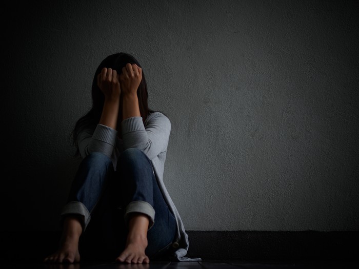 sad woman hug her knee and cry. Sad woman sitting alone in a empty room.