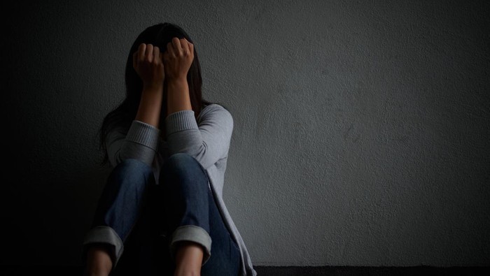 sad woman hug her knee and cry. Sad woman sitting alone in a empty room.