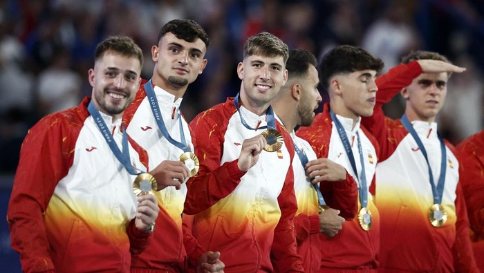 Paris 2024 Olympics - Football - Mens Victory Ceremony - Parc des Princes, Paris, France - August 09, 2024. Gold medallist Juan Miranda of Spain celebrates with Arnau Tenas of Spain and Marc Pubill of Spain on the podium. REUTERS/Benoit Tessier