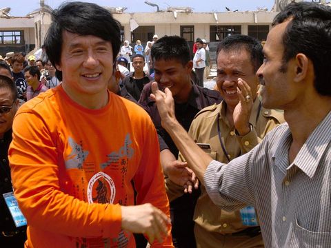 Hong Kong's action film hero Jackie Chan (L) shakes hands with villagers as he visits Indonesia's tsunami-ravaged city of Banda Aceh, 18 April 2005. Chan met orphans of the disaster and delighted local ethnic Chinese fans, also visiting a school in a district of the city hard hit by the December 26 disaster.   AFP PHOTO (Photo by AFP / AFP)