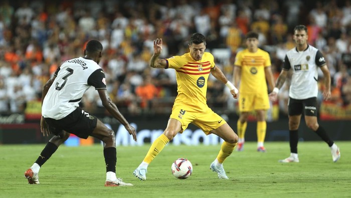 Barcelonas Robert Lewandowski, centre, and Valencias Cristhian Mosquera challenge for the ball during the Spanish La Liga soccer match between Valencia and FC Barcelona at the Mestalla stadium in Valencia, Spain, Saturday, Aug. 17, 2024. (AP Photo/Alberto Saiz)