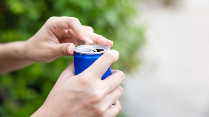 1318274414 Closeup woman hand open cola can with nature background minuman berenergi