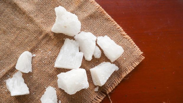 alum, Crystal clear alum stones or Potassium alum on plate, decorated with flowers. Useful for beauty and spa treatment. Use to treat body odor under the armpits as deodorant and make water clear.