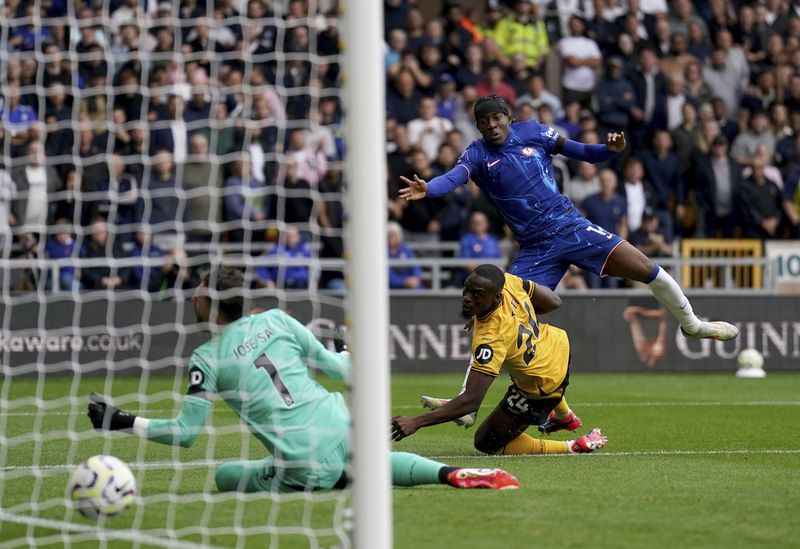 Chelsea's Noni Madueke, top, scores during the English Premier League soccer match between Wolverhampton Wanderers and Chelsea at Molineux Stadium, Wolverhampton, England. Sunday Aug. 25, 2024. (Joe Giddens/PA via AP)