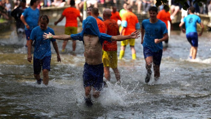 A player celebrates scoring during the annual football match in the River Windrush in Bourton-on-the-Water, Gloucestershire, Britain, August 26, 2024. REUTERS/Lee Smith