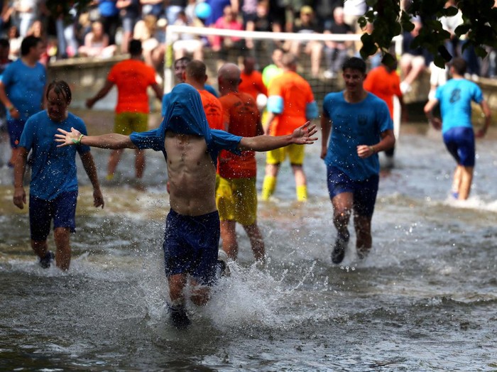 A player celebrates scoring during the annual football match in the River Windrush in Bourton-on-the-Water, Gloucestershire, Britain, August 26, 2024. REUTERS/Lee Smith