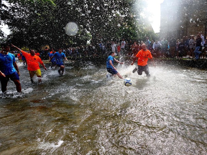 A player celebrates scoring during the annual football match in the River Windrush in Bourton-on-the-Water, Gloucestershire, Britain, August 26, 2024. REUTERS/Lee Smith