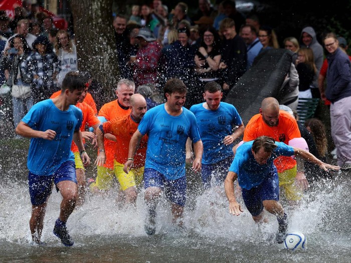 A player celebrates scoring during the annual football match in the River Windrush in Bourton-on-the-Water, Gloucestershire, Britain, August 26, 2024. REUTERS/Lee Smith