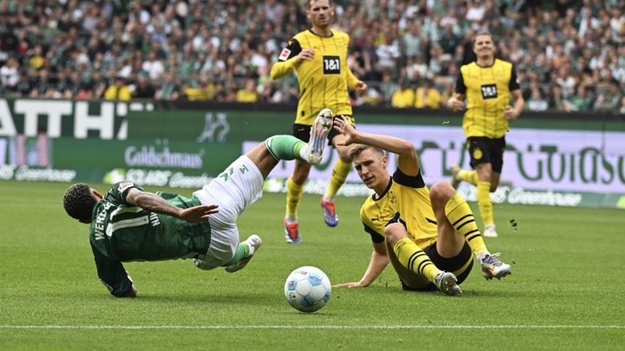 Dortmunds Nico Schlotterbeck, right, fouls Werders Justin Njinmah during the German Bundesliga soccer match between Werder Bremen and Borussia Dortmund in Bremen, Germany, Saturday, Aug. 31, 2024. (Carmen Jaspersen/dpa via AP)