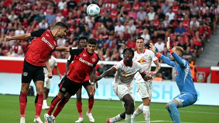 31 August 2024, North Rhine-Westphalia, Leverkusen: Soccer: Bundesliga, Bayer Leverkusen - RB Leipzig, Matchday 2, in the BayArena, Leverkusens Martin Terrier (l) and Leipzig goalkeeper Peter Gulacsi fight for the ball. Photo: Federico Gambarini/dpa - IMPORTANT NOTE: In accordance with the regulations of the DFL German Football League and the DFB German Football Association, it is prohibited to utilize or have utilized photographs taken in the stadium and/or of the match in the form of sequential images and/or video-like photo series. (Photo by Federico Gambarini/picture alliance via Getty Images)