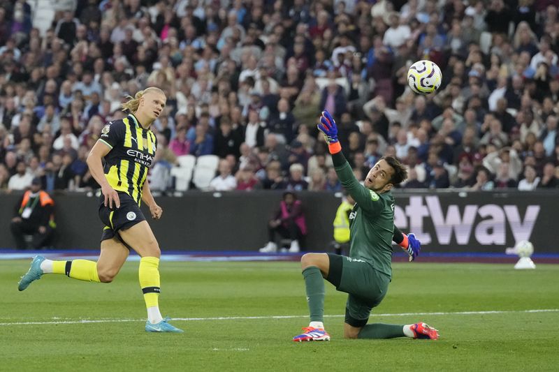 Manchester City's Erling Haaland, left, scores his side's third goal during the English Premier League soccer match between West Ham United and Manchester City at the London Stadium in London, England, Saturday, Aug. 31, 2024. (AP Photo/Frank Augstein)