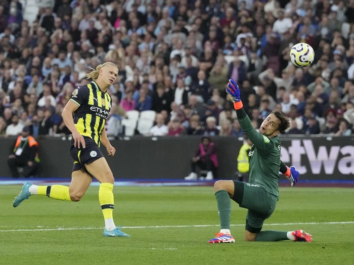 Manchester City's Erling Haaland, left, scores his side's third goal during the English Premier League soccer match between West Ham United and Manchester City at the London Stadium in London, England, Saturday, Aug. 31, 2024. (AP Photo/Frank Augstein)