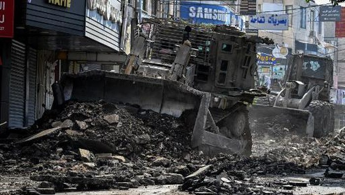 PALESTINIAN-ISRAEL-CONFLICT An Israeli bulldozer tears up a street as members of the press film during an Israeli raid in the occupied West Bank city of Jenin on September 1, 2024. (Photo by RONALDO SCHEMIDT / AFP)