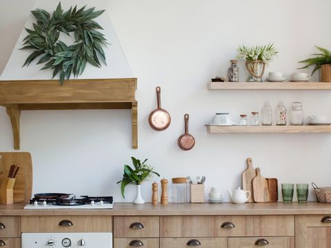 1296111659 Light wooden kitchen interior with kitchen utensils on the shelves and on the wall. Beautiful kitchen interior design