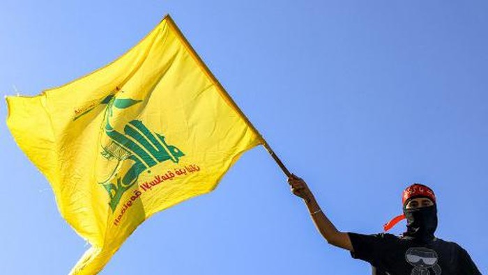 A masked demonstrator waves a flag of the Lebanese Shiite movement Hezbollah during a demonstration supporting the Palestinians in Beirut on October 20, 2023, amid the ongoing battles between Israel and the Palestinian group Hamas. (Photo by JOSEPH EID / AFP)