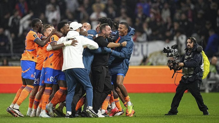 Marseille players and staff celebrate after scoring their second goal during a French League One soccer match between against Lyon at the Groupama stadium in Decines, outside Lyon, France, Sunday, Sept. 22, 2024. (AP Photo/Laurent Cipriani)