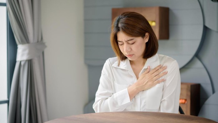 Ilustrasi jantung koroner atau sakit dada An Asian woman clutched her chest due to suffering from a sudden heart attack.