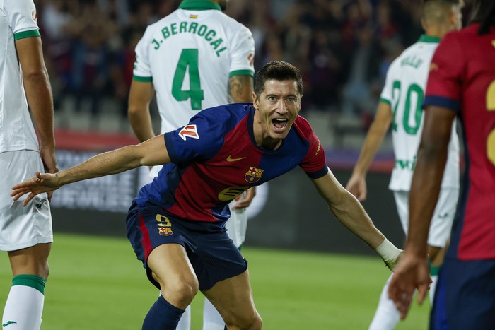 Spain Soccer La Liga Barcelona's Robert Lewandowski, center, celebrates with Barcelona's Jules Kounde, front, after scoring the opening goal during a Spanish La Liga soccer match between Barcelona and Getafe at the Olympic stadium in Barcelona, Spain, Wednesday, Sept. 25, 2024. (AP Photo/Joan Monfort)