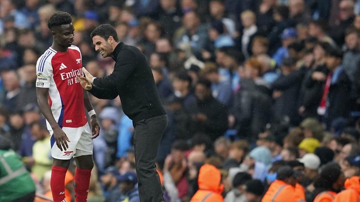 Arsenals manager Mikel Arteta speaks to Arsenals Bukayo Saka during the English Premier League soccer match between Manchester City and Arsenal at the Etihad stadium in Manchester, England, Sunday, Sept. 22, 2024. (AP Photo/Dave Thompson)
