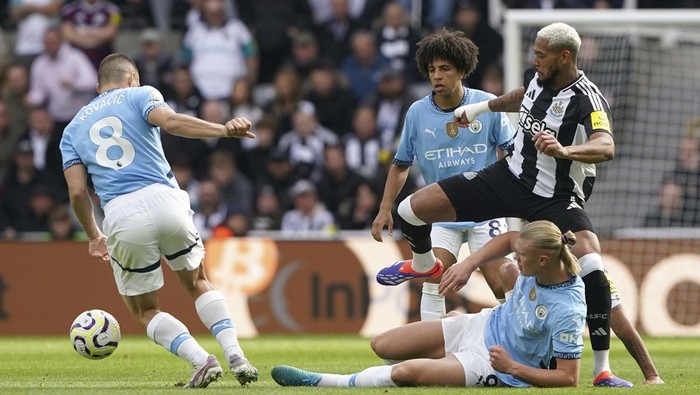 Newcastle Uniteds Joelinton, right, battles with Manchester Citys Mateo Kovacic, left, Erling Haaland, on the ground, and Rico Lewis, center, during the Premier League match between Newcastle and Manchester City, at St James Park, Newcastle upon Tyne, England, Saturday Sept. 28, 2024. (Owen Humphreys/PA via AP)
