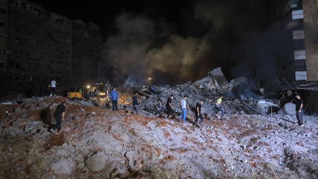 People and first responders stand on the rubble of a builiding destroyed in an Israeli air strike in the Haret Hreik neighbourhood of Beirut's southern suburbs on September 27, 2024. Israel carried out air strikes on the south of Lebanon's capital Beirut on September 27 that it said targeted Hezbollah's headquarters, moments after Prime Minister Benjamin Netanyahu vowed to keep fighting the militant group. (Photo by AFP)