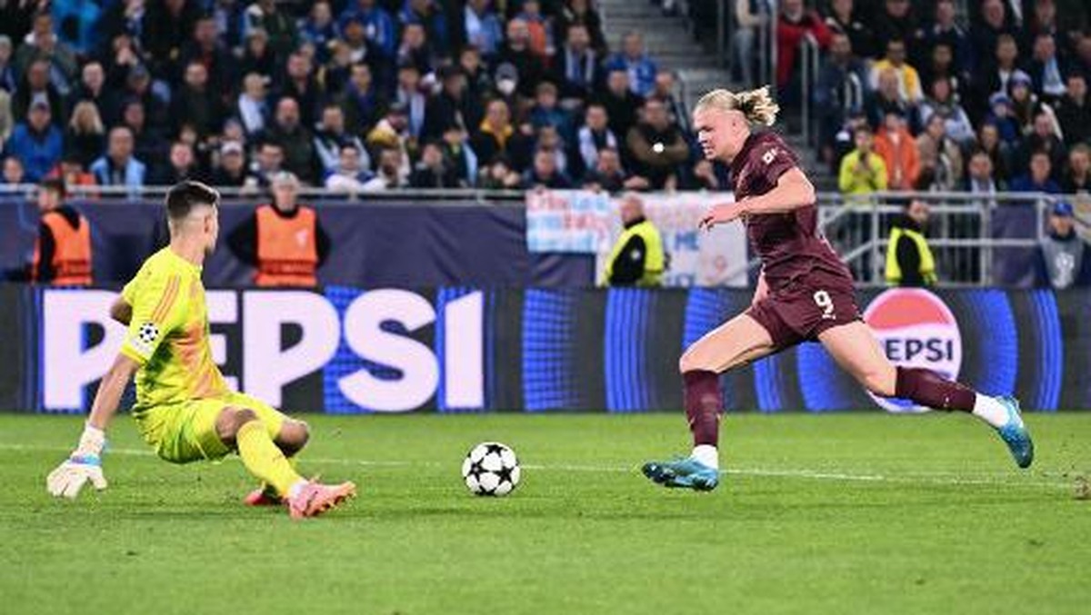 Erling Haaland (kanan) mengecoh kiper Slovan Bratislava, Dominik Takac sebelum mencetak gol ketiga Manchester City. Foto: AFP/JOE KLAMAR