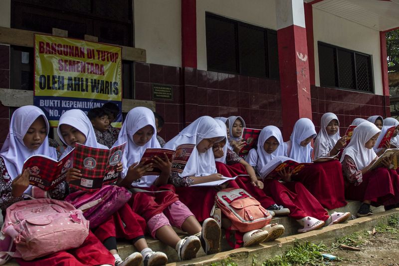 Siswa membaca buku di depan ruang kelas yang disegel di SDN Senangsari, Kecamatan Pagelaran, Pandeglang, Banten, Kamis (3/10/2024). Menurut pihak sekolah ruang kelas baru (RKB) yang diperuntukkan bagi siswa kelas enam tersebut telah disegel pihak yang mengaku ahli waris, sehingga kegiatan belajar mengajar terpaksa dilakukan di teras kelas atau dipindahkan ke ruang kelas lain yang tersedia. ANTARA FOTO/Angga Budhiyanto/Spt.