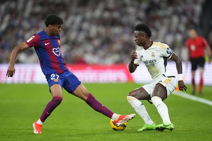 Barcelonas Lamine Yamal, left, fights for the ball with Real Madrids Vinicius Junior during the Spanish La Liga soccer match between Real Madrid and Barcelona at the Santiago Bernabeu stadium in Madrid, Spain, Sunday, April 21, 2024. (AP Photo/Manu Fernandez)
