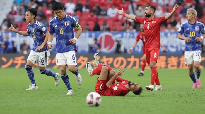 DOHA, QATAR - JANUARY 31: Ali Madan of Bahrain falls under pressure from Wataru Endo and Seiya Maikuma of Japan during the AFC Asian Cup Round of 16 match between Bahrain and Japan at Al Thumama Stadium on January 31, 2024 in Doha, Qatar. (Photo by Lintao Zhang/Getty Images)