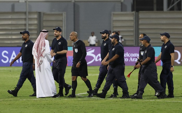 Soccer Football - World Cup - Asian Qualifiers - Third Round - Group C - Bahrain v Indonesia - Bahrain National Stadium, Riffa, Bahrain - October 10, 2024 Referee Ahmed Al-Kaf with police after the match REUTERS/Hamad I Mohammed