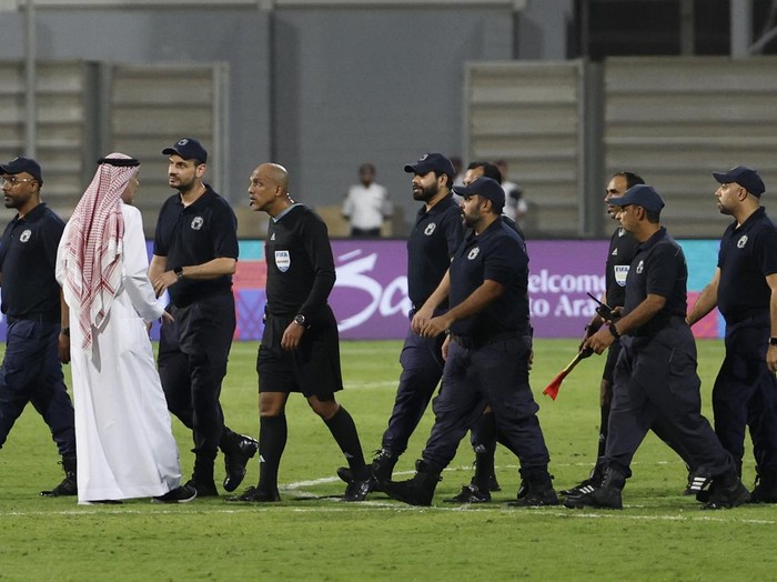 Soccer Football - World Cup - Asian Qualifiers - Third Round - Group C - Bahrain v Indonesia - Bahrain National Stadium, Riffa, Bahrain - October 10, 2024 Referee Ahmed Al-Kaf with police after the match REUTERS/Hamad I Mohammed