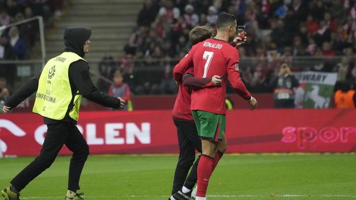Cristiano Ronaldo A pitch invader takes a selfie with Portugals Cristiano Ronaldo as he left the pitch after being substituted during the UEFA Nations League soccer match between Poland and Portugal at Narodowy stadium in Warsaw, Poland, Saturday, Oct. 12, 2024. (AP Photo/Czarek Sokolowski)