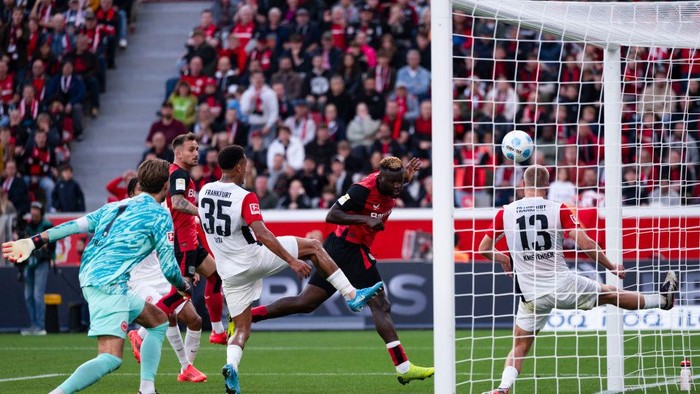 19 October 2024, North Rhine-Westphalia, Leverkusen: Soccer: Bundesliga, Bayer Leverkusen - Eintracht Frankfurt, Matchday 7, BayArena. Leverkusens Victor Boniface (2nd from right) scores for a 2:1 lead. Frankfurts Rasmus Kristensen on the right. On the left, Frankfurts Kevin Trapp and Tuta. Photo: Marius Becker/dpa - IMPORTANT NOTE: In accordance with the regulations of the DFL German Football League and the DFB German Football Association, it is prohibited to utilize or have utilized photographs taken in the stadium and/or of the match in the form of sequential images and/or video-like photo series. (Photo by Marius Becker/picture alliance via Getty Images)