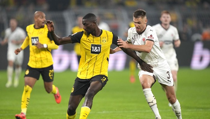 St. Paulis Karol Mets, right, and Dortmunds Serhou Yadaly Guirassy challenge for the ball during the German Bundesliga soccer match between Borussia Dortmund and St. Pauli at the Signal-Iduna Park in Dortmund, Germany, Friday, Oct. 18, 2024. (AP Photo/Martin Meissner)