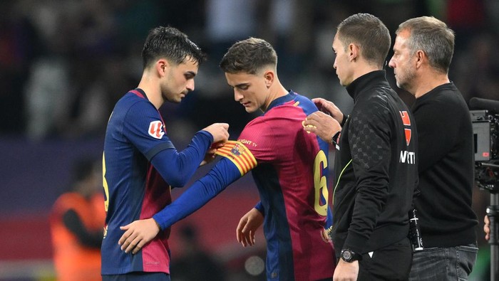 BARCELONA, SPAIN - OCTOBER 20: Pedri of FC Barcelona attaches the captains armband onto the arm of teammate Gavi whilst being substituted during the La Liga EA Sports match between FC Barcelona and Sevilla FC at Estadi Olimpic Lluis Companys on October 20, 2024 in Barcelona, Spain. (Photo by David Ramos/Getty Images)
