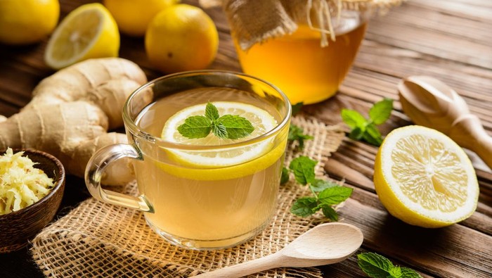 Ilustrasi minuman jahe lemon madu Cup of ginger root tea with lemon, honey and mint on a wooden background