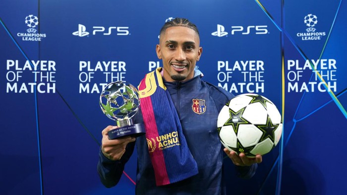 BARCELONA, SPAIN - OCTOBER 23: Raphinha of FC Barcelona poses for a photo with the PlayStation Player Of The Match award and match ball after his hat-trick during the teams victory in the UEFA Champions League 2024/25 League Phase MD3 match between FC Barcelona and FC Bayern Munchen at Estadi Olimpic Lluis Companys on October 23, 2024 in Barcelona, Spain. (Photo by Alex Caparros - UEFA/UEFA via Getty Images)