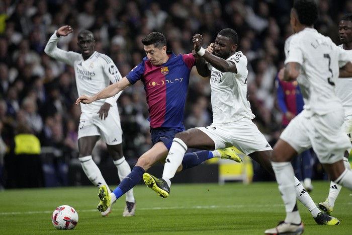 Barcelonas Robert Lewandowski fights for the ball against Real Madrids Antonio Rudiger during a Spanish La Liga soccer match between Real Madrid and Barcelona at the Santiago Bernabeu stadium in Madrid, Spain, Saturday, Oct. 26, 2024. (AP Photo/Bernat Armangue)