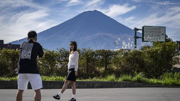 Warga beraktivitas dengan latar belakang Gunung Fuji, gunung tertinggi di Jepang dengan ketinggian 3.776 meter (12.460 kaki), di Fujikawaguchiko, prefektur Yamanashi pada tanggal 31 Oktober 2024. (AFP/YUICHI YAMAZAKI)