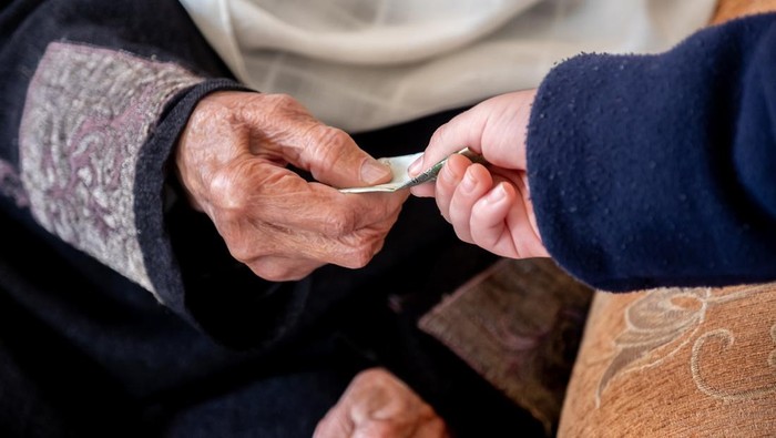 Ilustrasi sedekah Hands of old woman giving money to her grandson during arabia eid