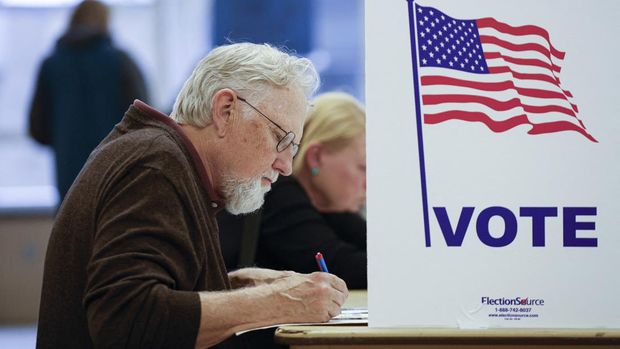 A man fills out his ballot during early voting for the US general election at a polling station at Ottawa Hills High School in Grand Rapids, Michigan, on November 3, 2024. (Photo by KAMIL KRZACZYNSKI / AFP)