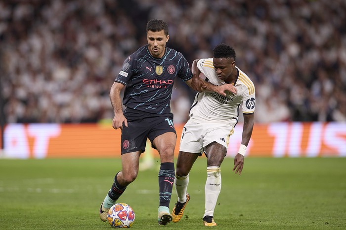 MADRID, SPAIN - 2024/04/09: Rodrigo Hernandez Cascante, known as Rodri (L) of Manchester City with Vinicius Junior (R) of Real Madrid CF in action during the UEFA Champions League 2023/2024 quarter-finals first leg football match between Real Madrid CF and Manchester City at Santiago Bernabeu stadium. Final score: Real Madrid CF 3:3 Manchester City. (Photo by Federico Titone/SOPA Images/LightRocket via Getty Images)