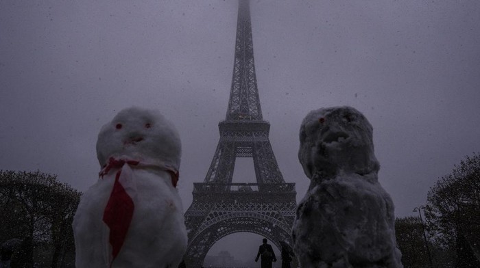 Salju Mulai Turun di Paris, Menara Eiffel Ditutup Sementara Snow figures are seen near to the Eiffel Tower as snow falls in Paris, Thursday, Nov. 21, 2024. (AP Photo/Louise Delmotte)