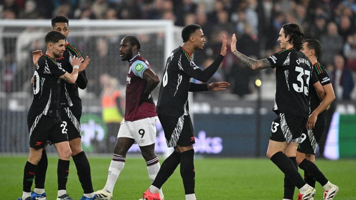LONDON, ENGLAND - NOVEMBER 30: Riccardo Calafiori of Arsenal celebrates with teammate Gabriel and Leandro Trossard after Kai Havertz of Arsenal (not pictured) scores his teams fourth goal during the Premier League match between West Ham United FC and Arsenal FC at London Stadium on November 30, 2024 in London, England. (Photo by Stuart MacFarlane/Arsenal FC via Getty Images)
