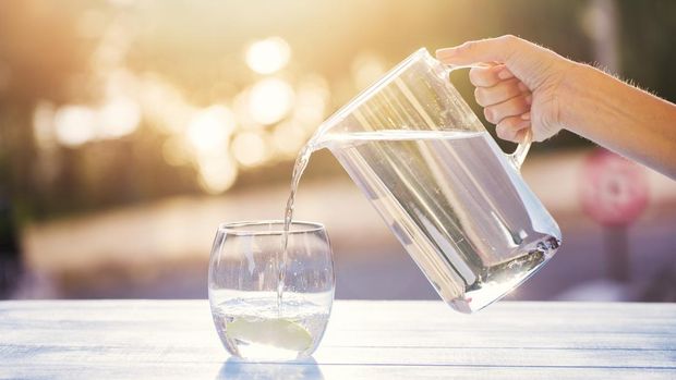 Hand Pouring Water From Pitcher Into Glass