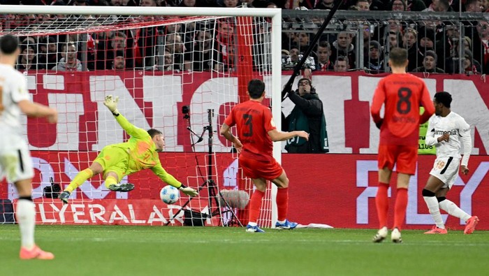 03 December 2024, Bavaria, Munich: Soccer, DFB Cup, FC Bayern Munich - Bayer 04 Leverkusen, round of 16, Allianz Arena, Leverkusens Nathan Tella (r) scores the goal against Munich goalkeeper Daniel Peretz to make it 1-0. IMPORTANT NOTE: In accordance with the regulations of the DFL German Football League and the DFB German Football Association, it is prohibited to exploit or have exploited photographs taken in the stadium and/or of the match in the form of sequential images and/or video-like photo series. Photo: Sven Hoppe/dpa (Photo by Sven Hoppe/picture alliance via Getty Images)