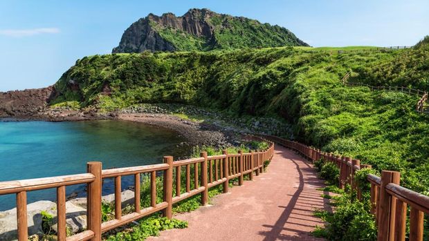 Pathway leading to beach with view over ocean and and volcano crater Ilchulbong, Seongsan, Jeju Island, South Korea