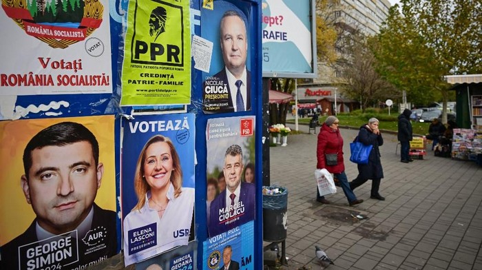 (FILES) In this file photo taken on November 22, 2024 pedestrians pass by electoral posters with candidates for the presidential and parliamentary elections in Bucharest. Romanias constitutional court announced on December 6, 2024 that it was cancelling the presidential election, where a run-off had been due to take place on December 8, 2024 amid allegations of Russian interference. The court has decided to annul the entire electoral process for the election of the President of Romania... to ensure the correctness and legality of the electoral process, it said. (Photo by Daniel MIHAILESCU / AFP)