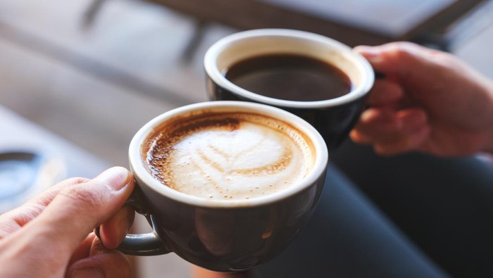 Ilustrasi kopi Closeup image of a man and a woman clinking white coffee mugs in cafe